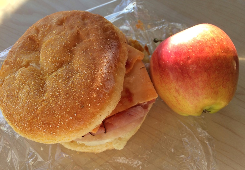 Photo of a glutino gluten free english muffin with ham and egg and an apple on the side 